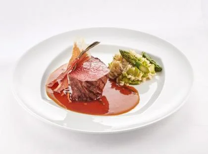 Ball Tip vom Rind mit getrocknetem Salbei und Parmaschinken, Spargelrisotto und Salbei-Weißweinjus auf weißen Teller