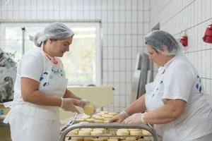 zwei Frauen beim Käseherstellung mit Salzlake bestreichen