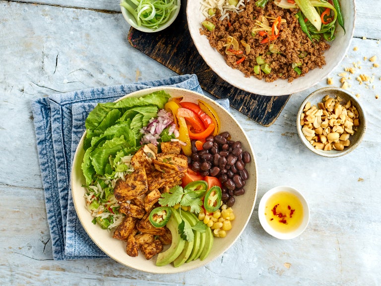 Tisch von oben, zwei Bowls mit pflanzlichen Produkten und Toppings