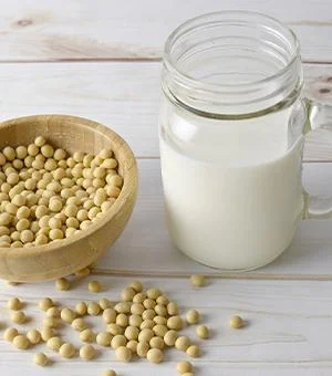 Vegane-Ernaehrung-Soja-Milch neben Sojabohnen in Schüssel