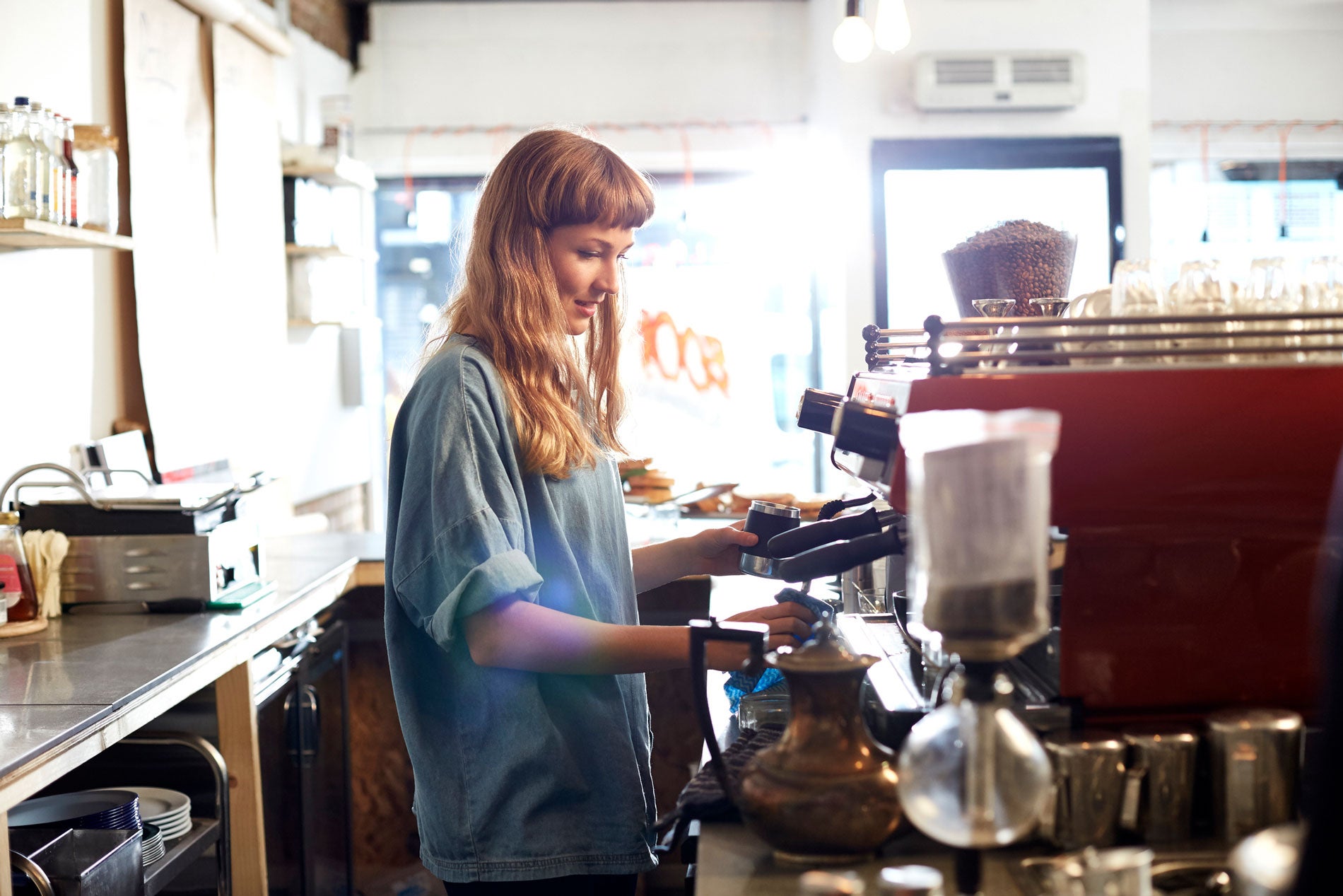 Frau an einem Kaffeeautomat in einem Café
