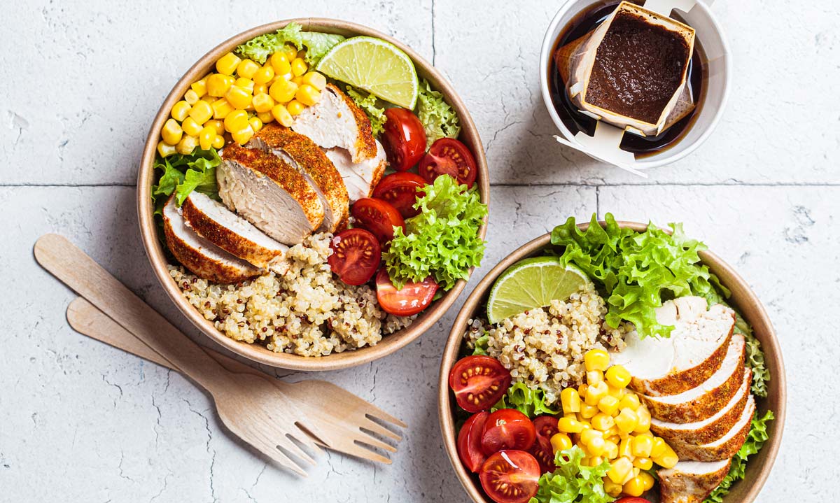 Hähnchen-Quinoa-Salat mit Mais und Tomaten in einer handgefertigten Öko-Schüssel. Zero Waste, Lebensmittel zum Mitnehmen, Recycling von Verpackungen, umweltfreundliches Konzept.