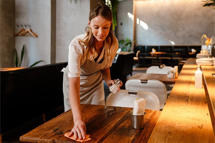 Frau desinfiziert den Tisch