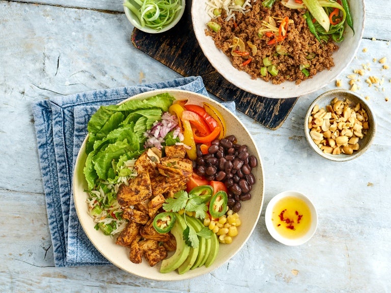 Tisch von oben, zwei Bowls mit pflanzlichen Produkten und Toppings