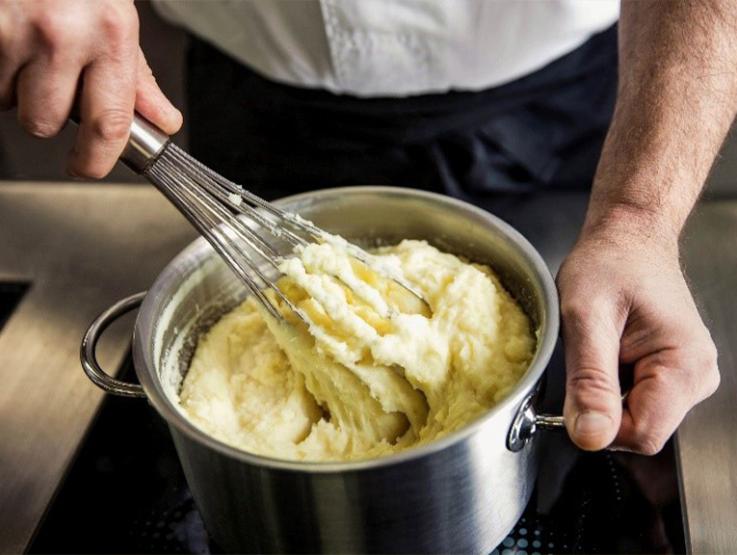 Topf mit Kartoffel Pürree wird mit Schneebesen gerührt