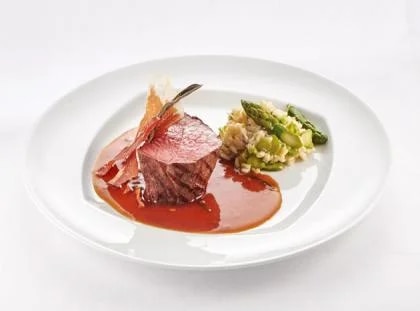 Ball Tip vom Rind mit getrocknetem Salbei und Parmaschinken, Spargelrisotto und Salbei-Weißweinjus auf weißen Teller