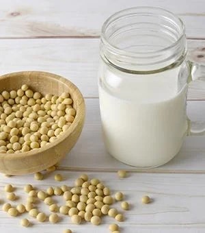 Vegane-Ernaehrung-Soja-Milch neben Sojabohnen in Schüssel