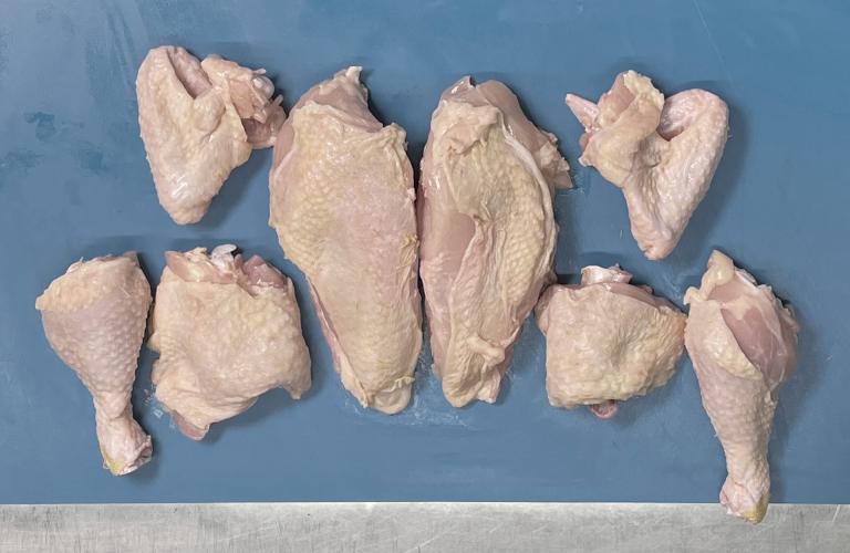 Zerlegtes ganzes Hähnchen auf blauen Untergrund