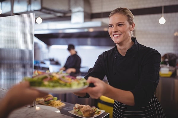 Eine Frau gibt an Kunden ein Essen