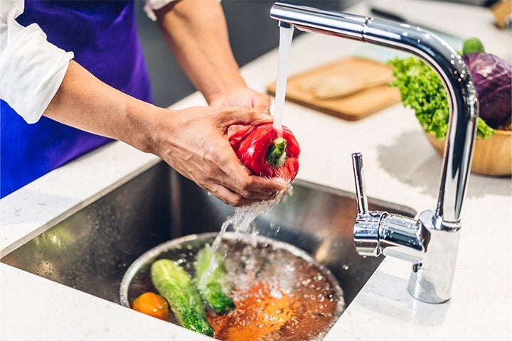 Koch wascht Paprika unter laufendem Wasser